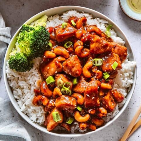 Chinese cashew chicken with rice and broccoli in a white bowl