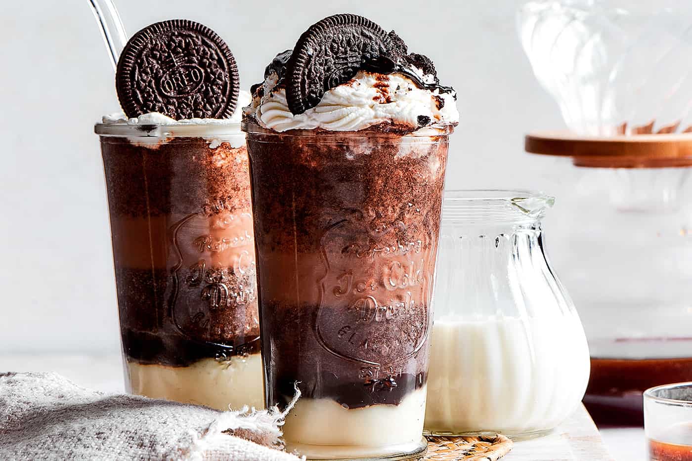 2 tall clear glasses of Frappuccino made with chocolate and cookie crumbles