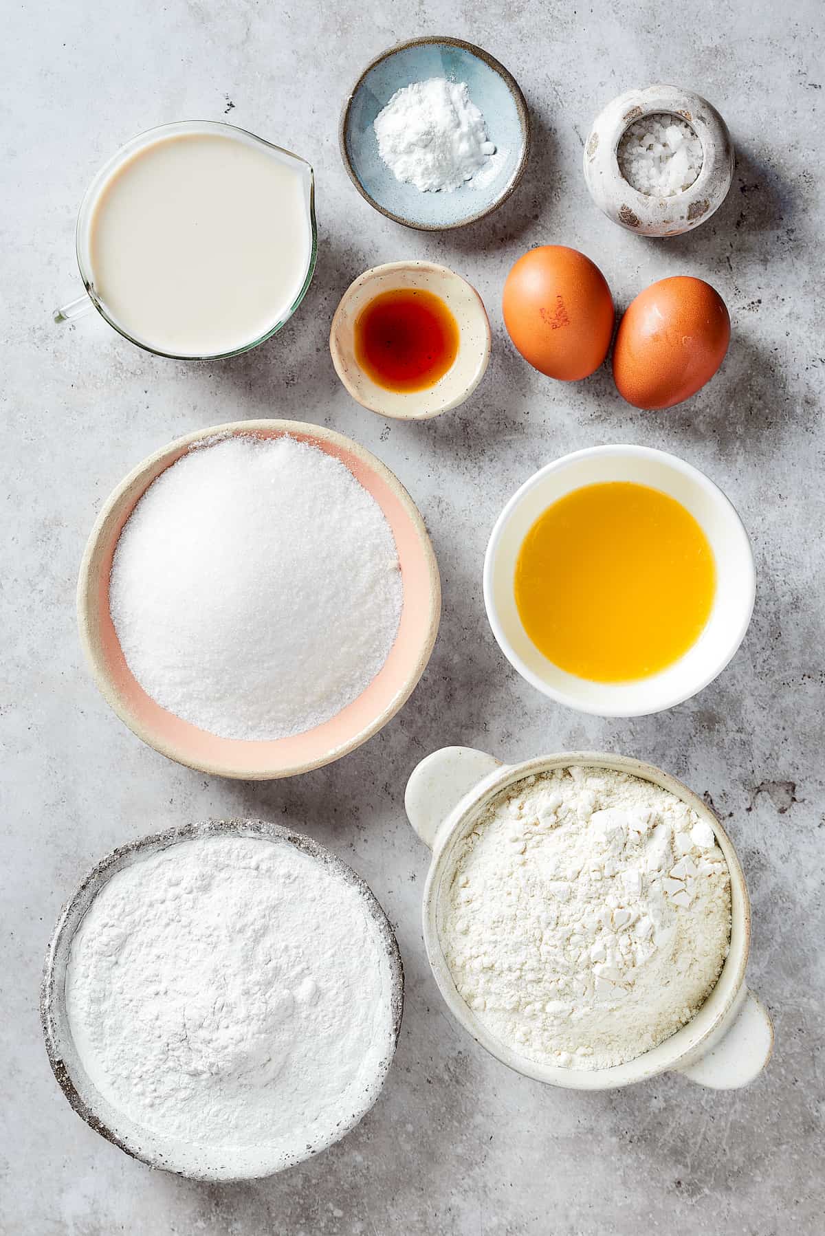 Ingredients to make strawberry crunch cake are shown in bowls, including flour, vanilla, sugar, powdered sugar, and eggs.