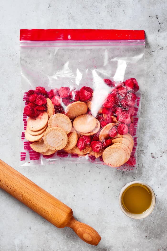 Oreos and freeze-dried strawberries are in a plastic bag ready to be pulverized with a baking pin.