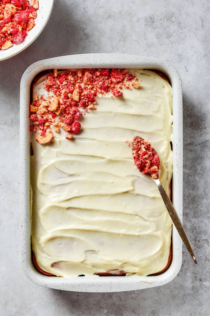 Adding crunch topping to a strawberry crunch cake.