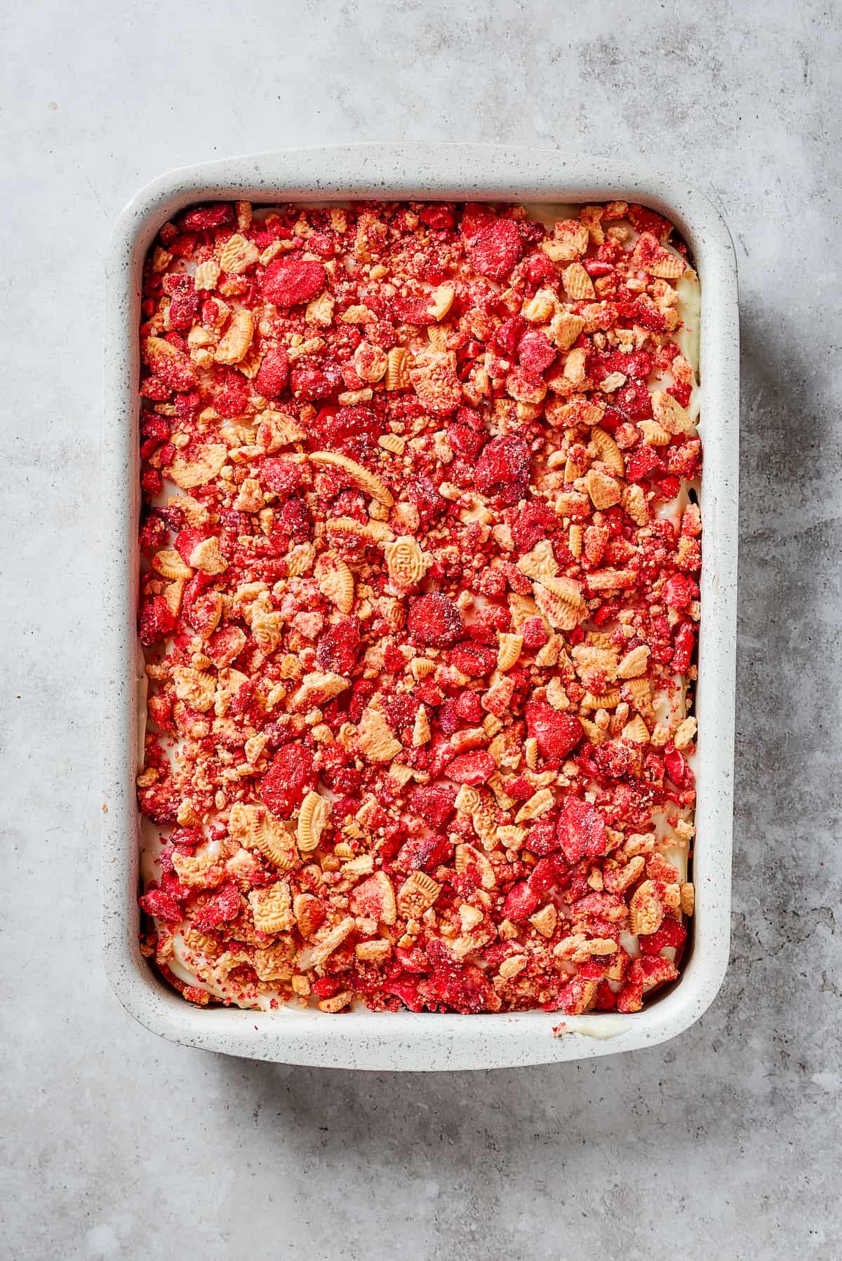 A finished strawberry crunch cake is shown in a pan.