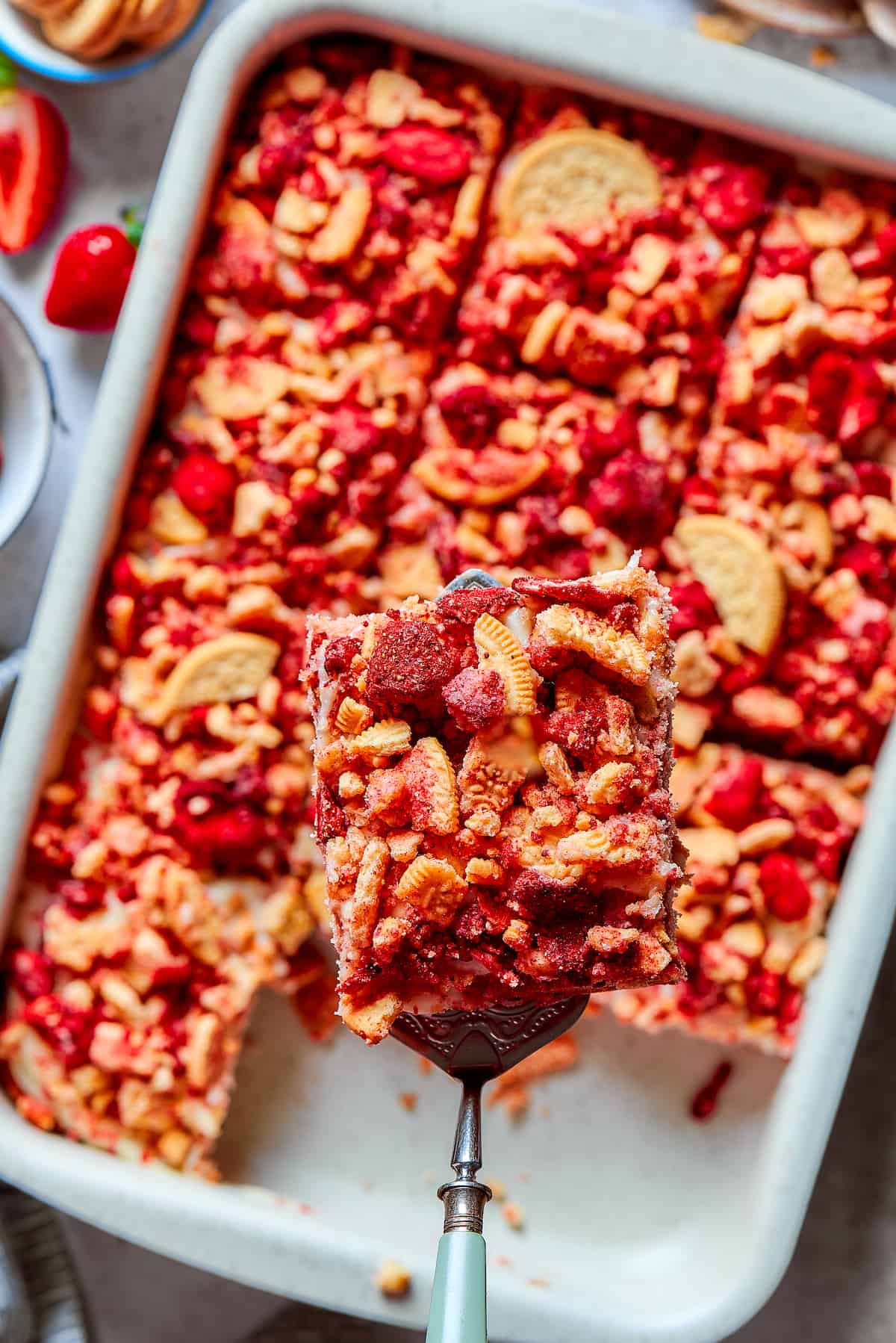 A piece of strawberry crunch cake is lifted out of a pan.