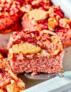 A piece of strawberry crunch cake is lifted out of a pan.