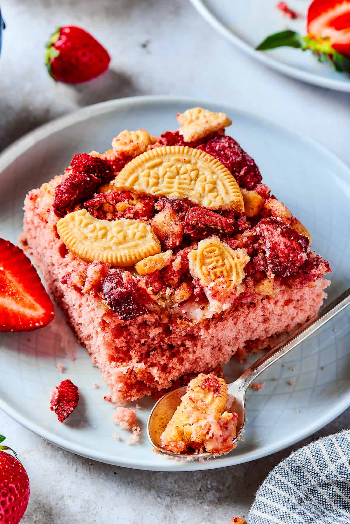 Pieces of strawberry crunch cake on plates with strawberries.