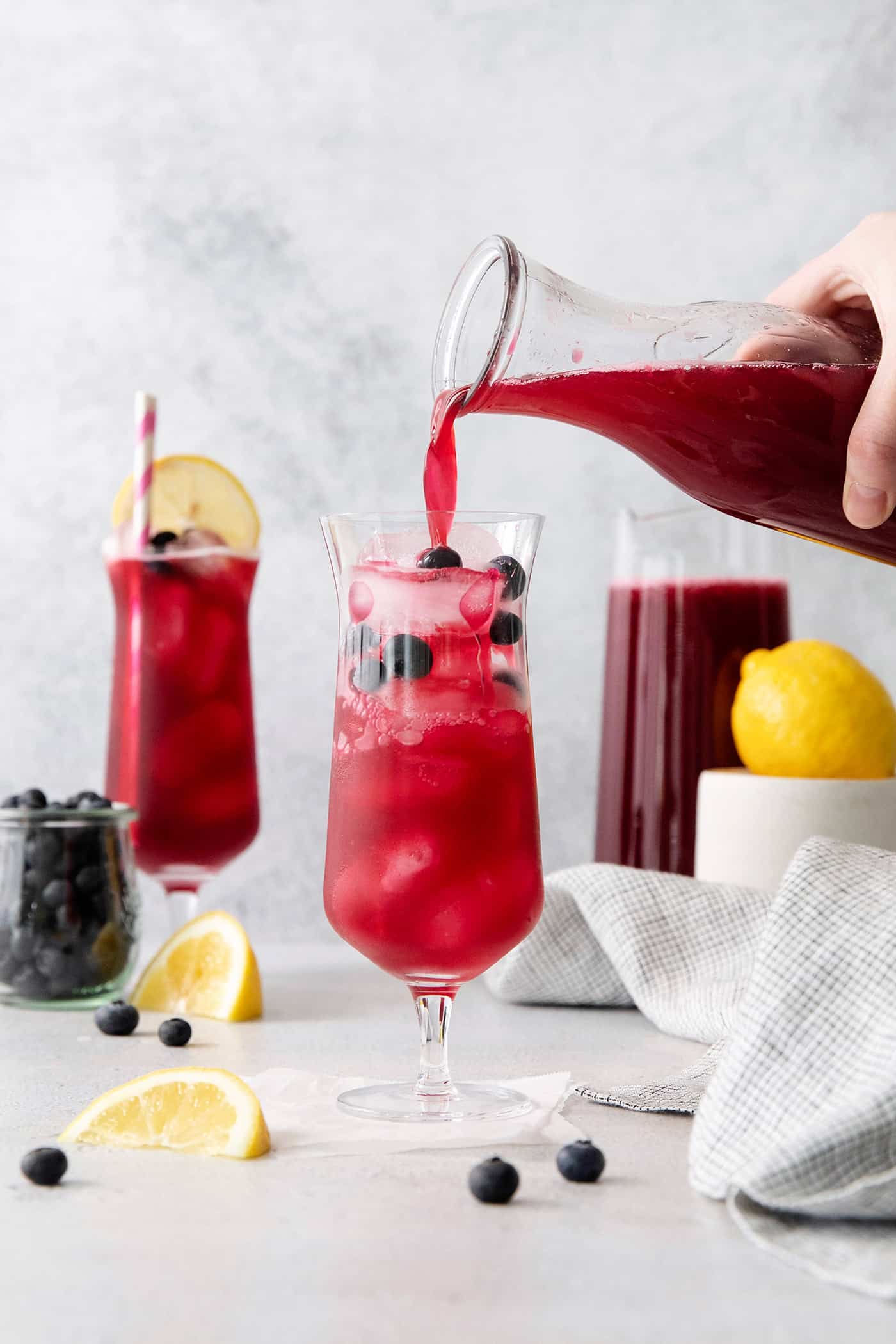 Blueberry lemonade being poured into a glass over ice