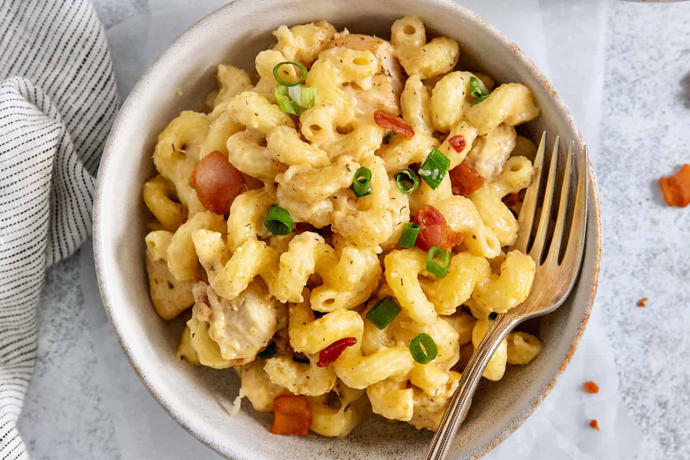 A bowl of chicken bacon ranch pasta on a white background with a fork.