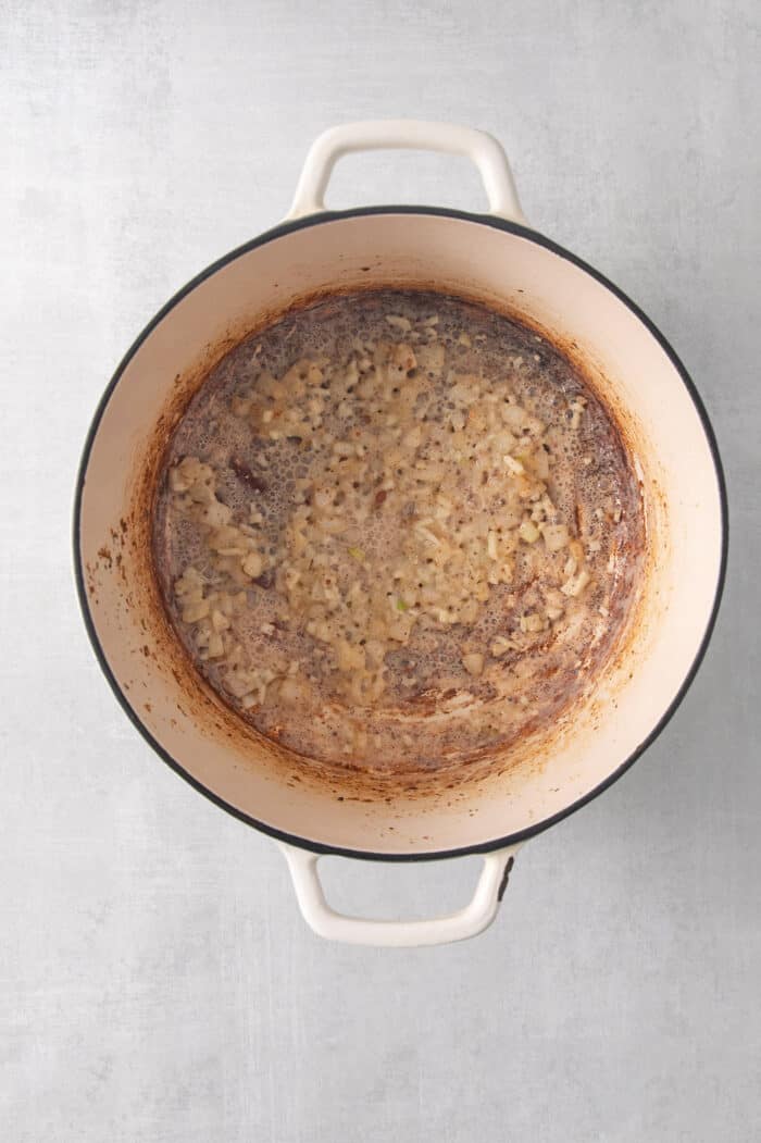 Onion is cooked in chicken drippings in a pot.