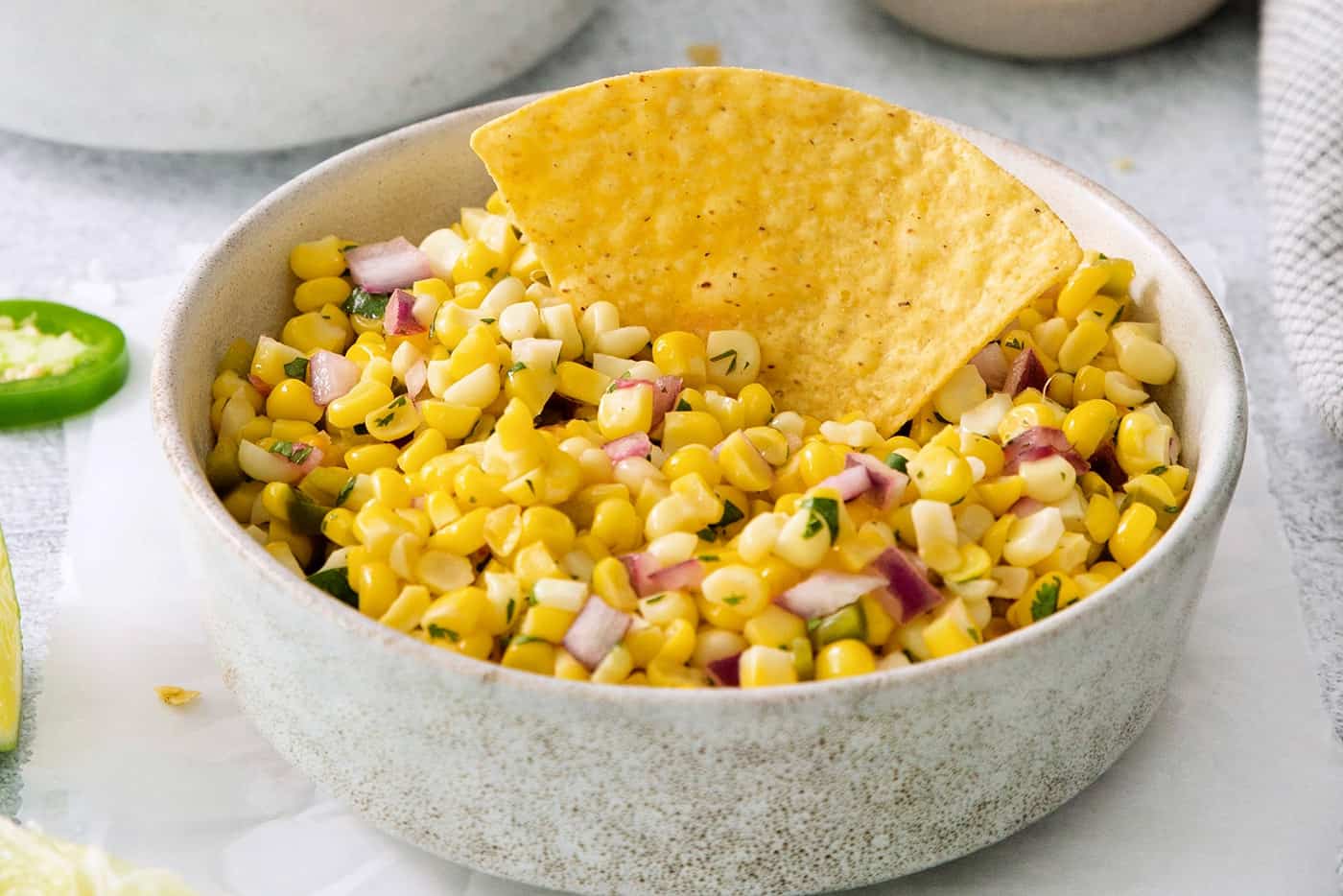 A tortilla chip in a bowl of roasted chili corn salsa