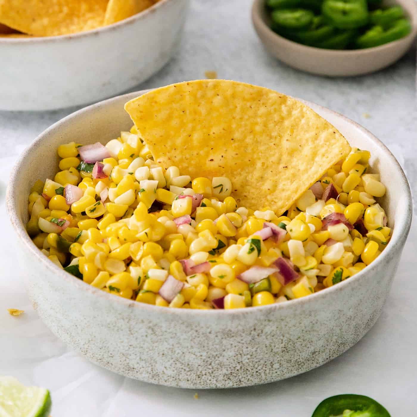 A tortilla chip in a bowl of corn salsa