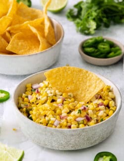 A tortilla chip in a bowl of Chipotle corn salsa