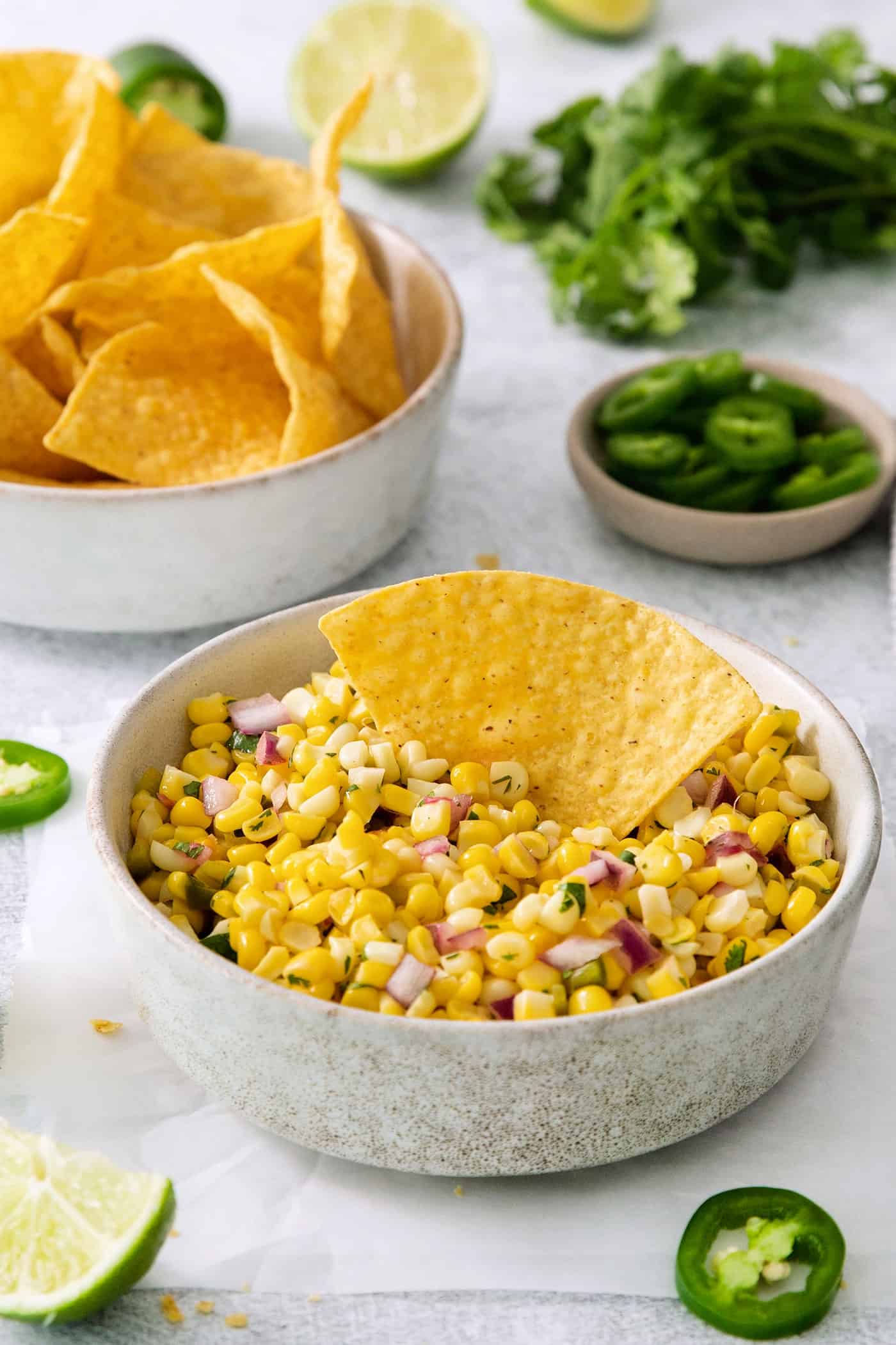 Roasted Chili Corn Salsa is a copycat of the addicting Chipotle side dish! Enjoy with chips, in a Tex-Mex bowl, or as a garnish for tacos! A tortilla chip in a bowl of Chipotle corn salsa