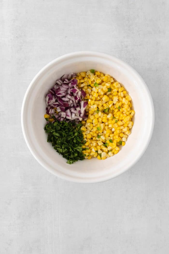 A bowl with corn, jalapeno, cilantro, and onion