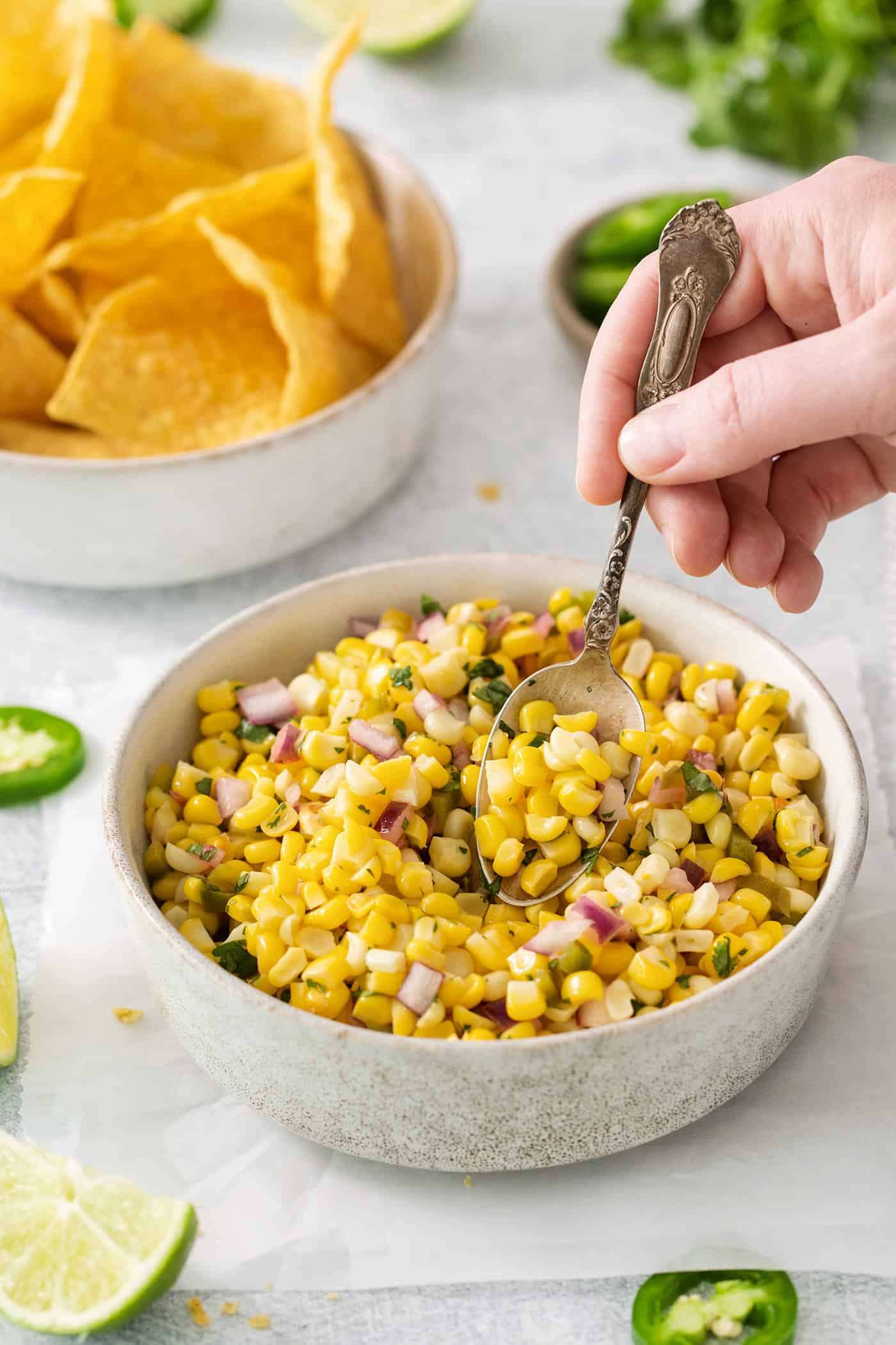 A spoon stirring a bowl of copycat Chipotle corn salsa