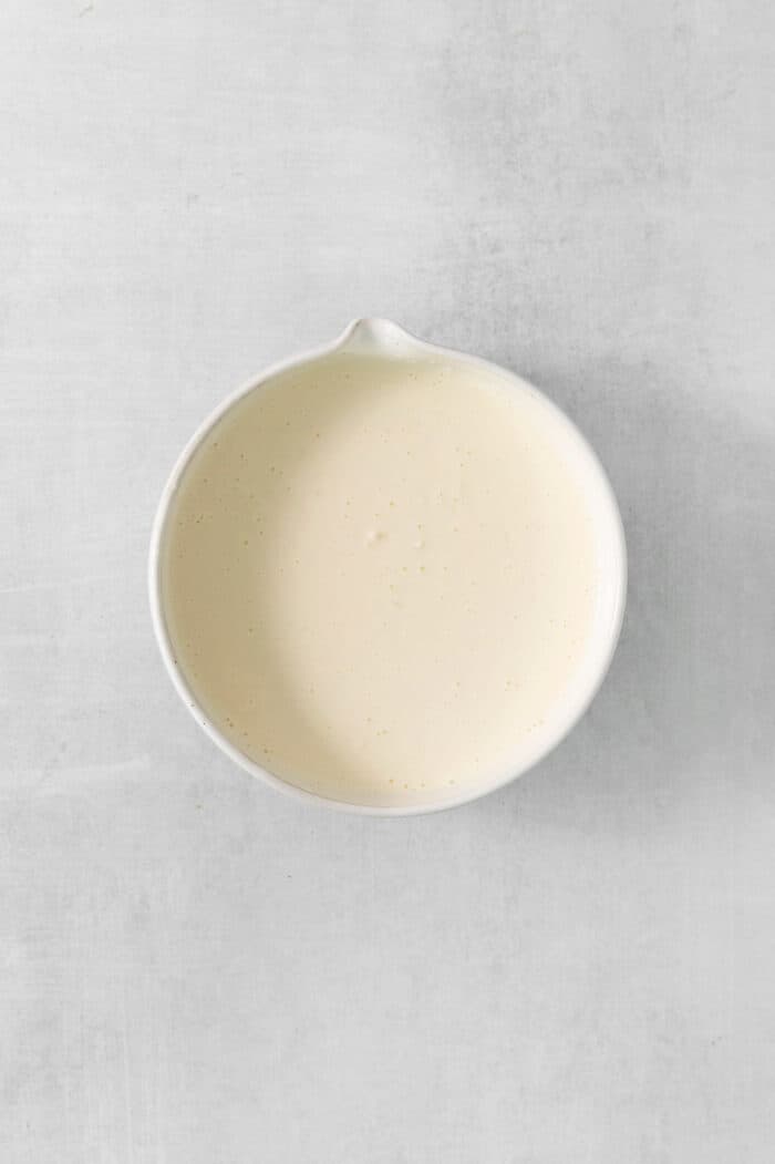 Mayonnaise dressing in a white bowl on a white background.
