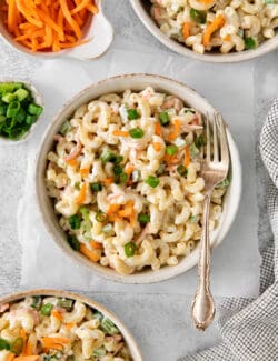 Bowls of hawaiian macaroni salad are seen in white bowls on a table with forks.