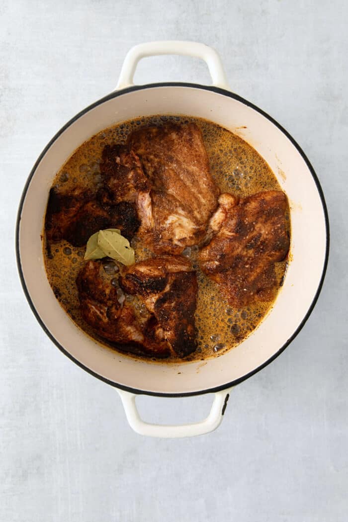 Pork cooks in a dutch oven.
