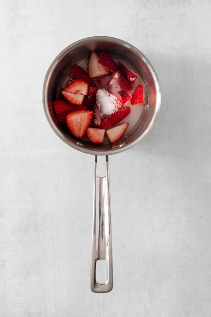 Mixing strawberries and sugar in a pot.