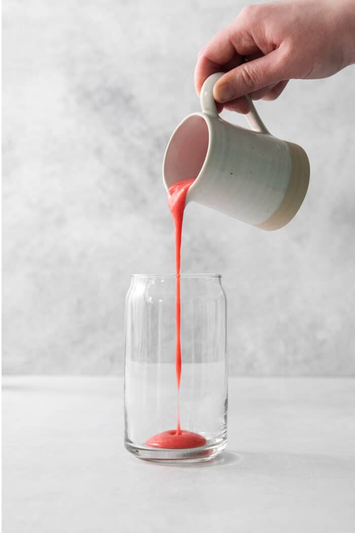 Pouring strawberry puree into a glass.