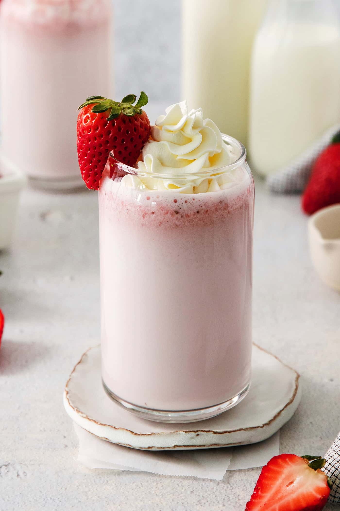 Glasses of strawberry milk with milk in the background.