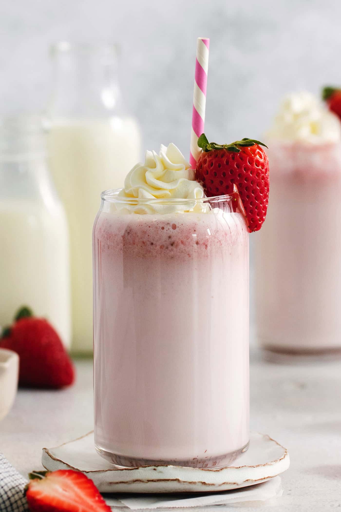 Glasses of strawberry milk with milk in the background.