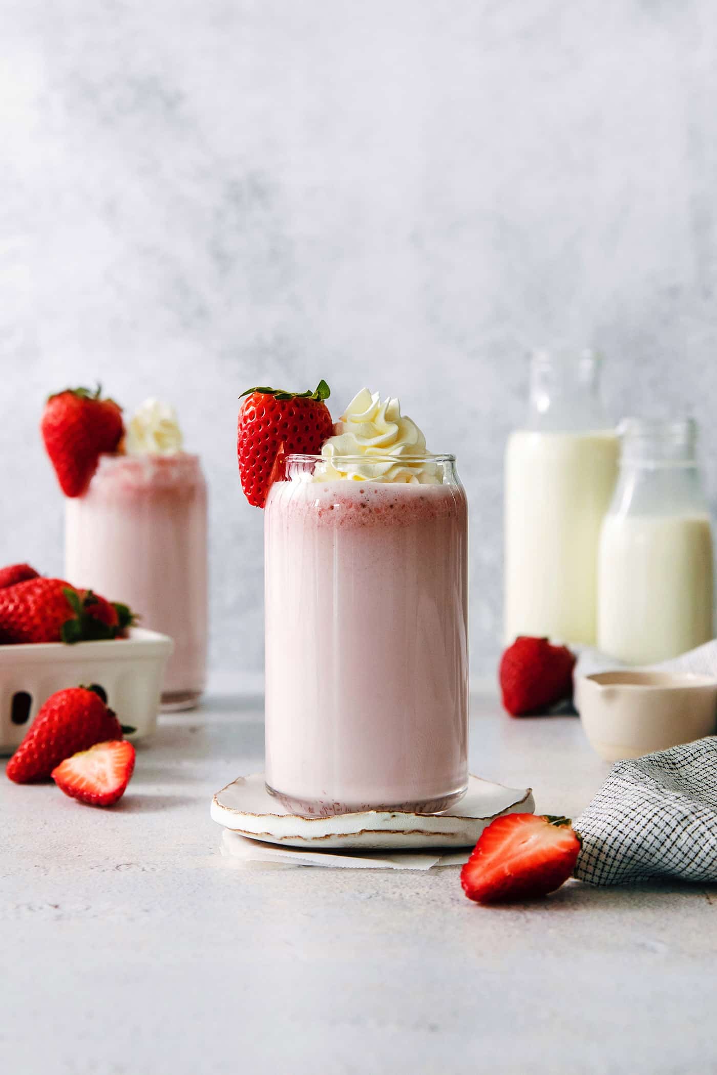 Glasses of strawberry milk with milk in the background.