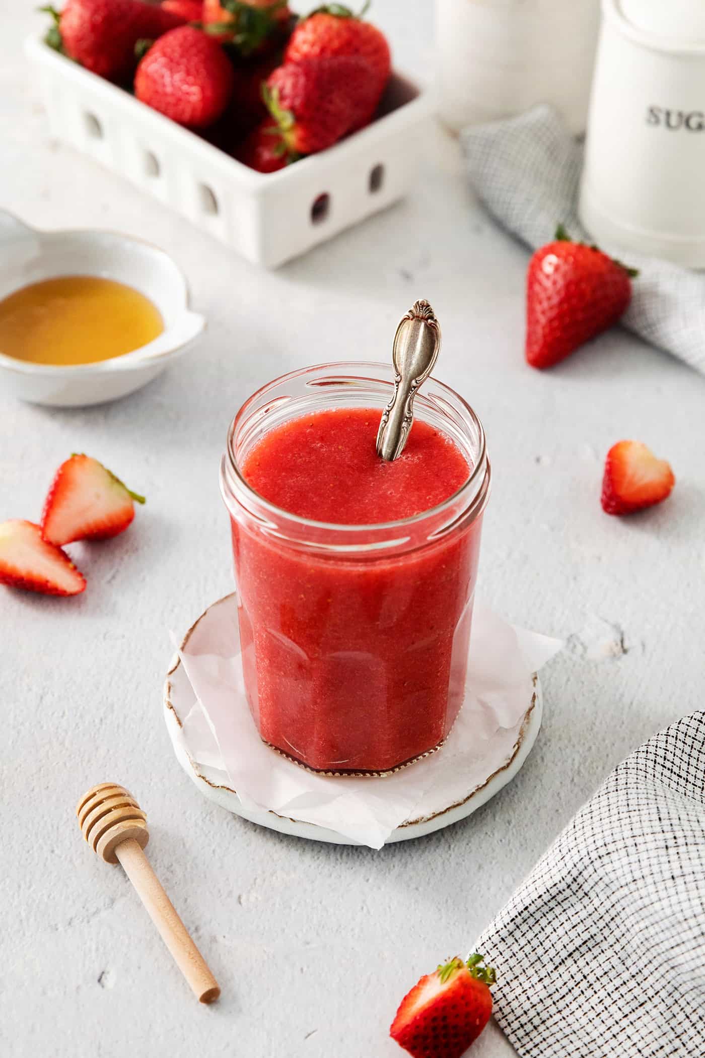 a jar of homemade strawberry sauce with a spoon in it