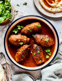 Rouladen in gravy in a bowl on a table.