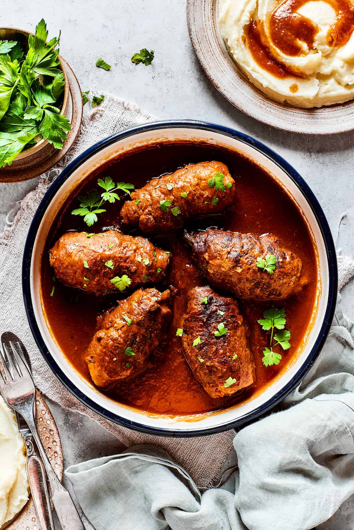 Rouladen in gravy in a bowl on a table.