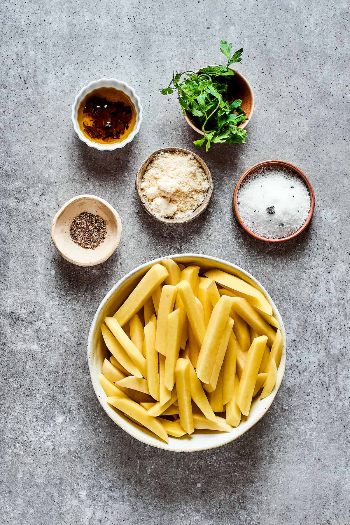 Ingredients needed to make truffle fries - potatoes, cheese, truffle salt, truffle oil, and parsley.