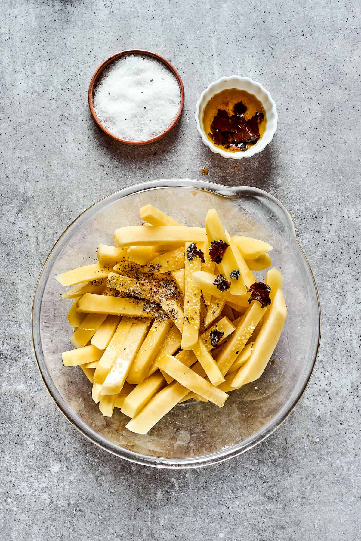 A bowl of cut potatoes for fries with seasonings.