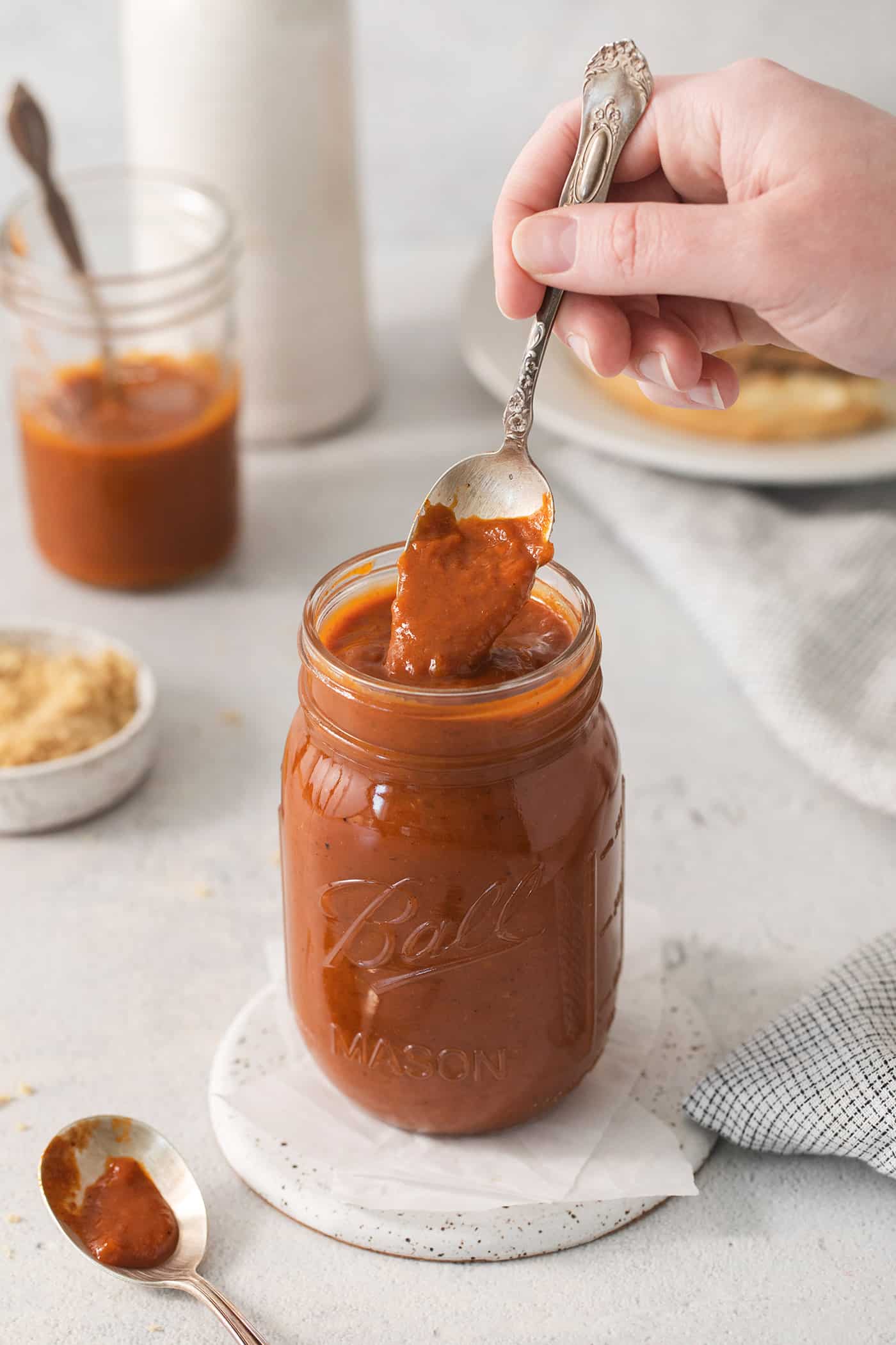 a spoon of homemade barbecue sauce from a jar of sauce