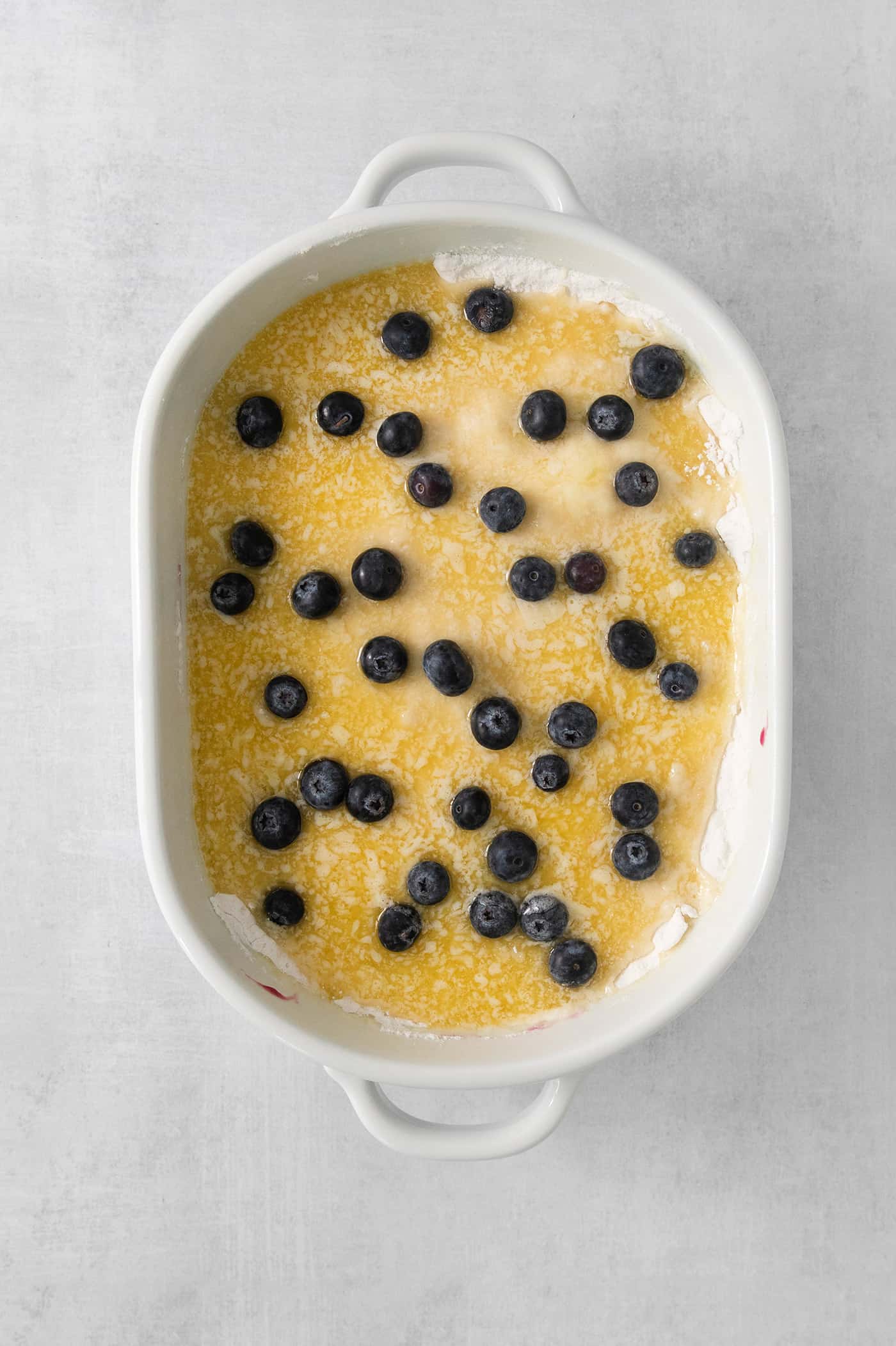 Assembling blueberry dump cake in a baking dish.