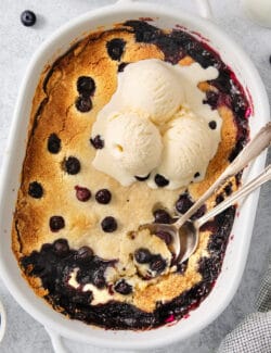 Blueberry dump cake in a pan topped with ice cream.