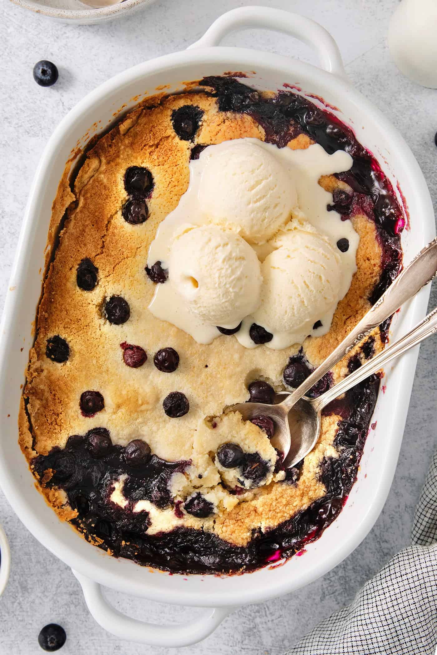 Blueberry dump cake in a pan topped with ice cream.