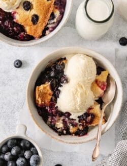 A bowl of blueberry dump cake topped with ice cream.