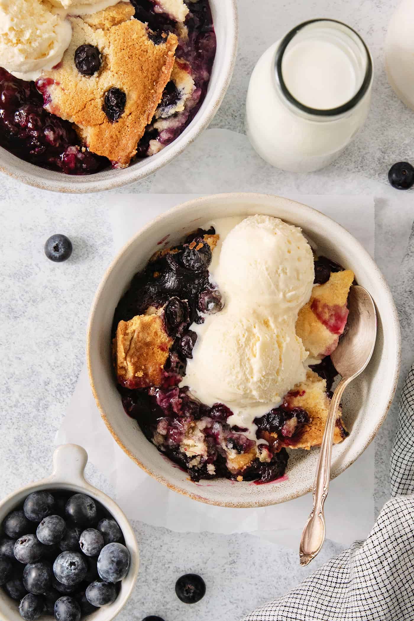 A bowl of blueberry dump cake topped with ice cream.