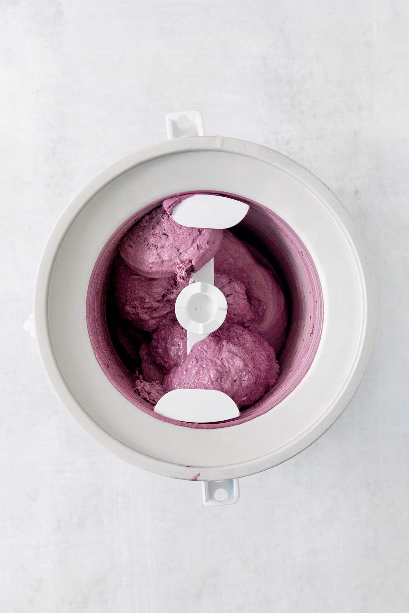Blueberry ice cream cream churns in an ice cream maker.