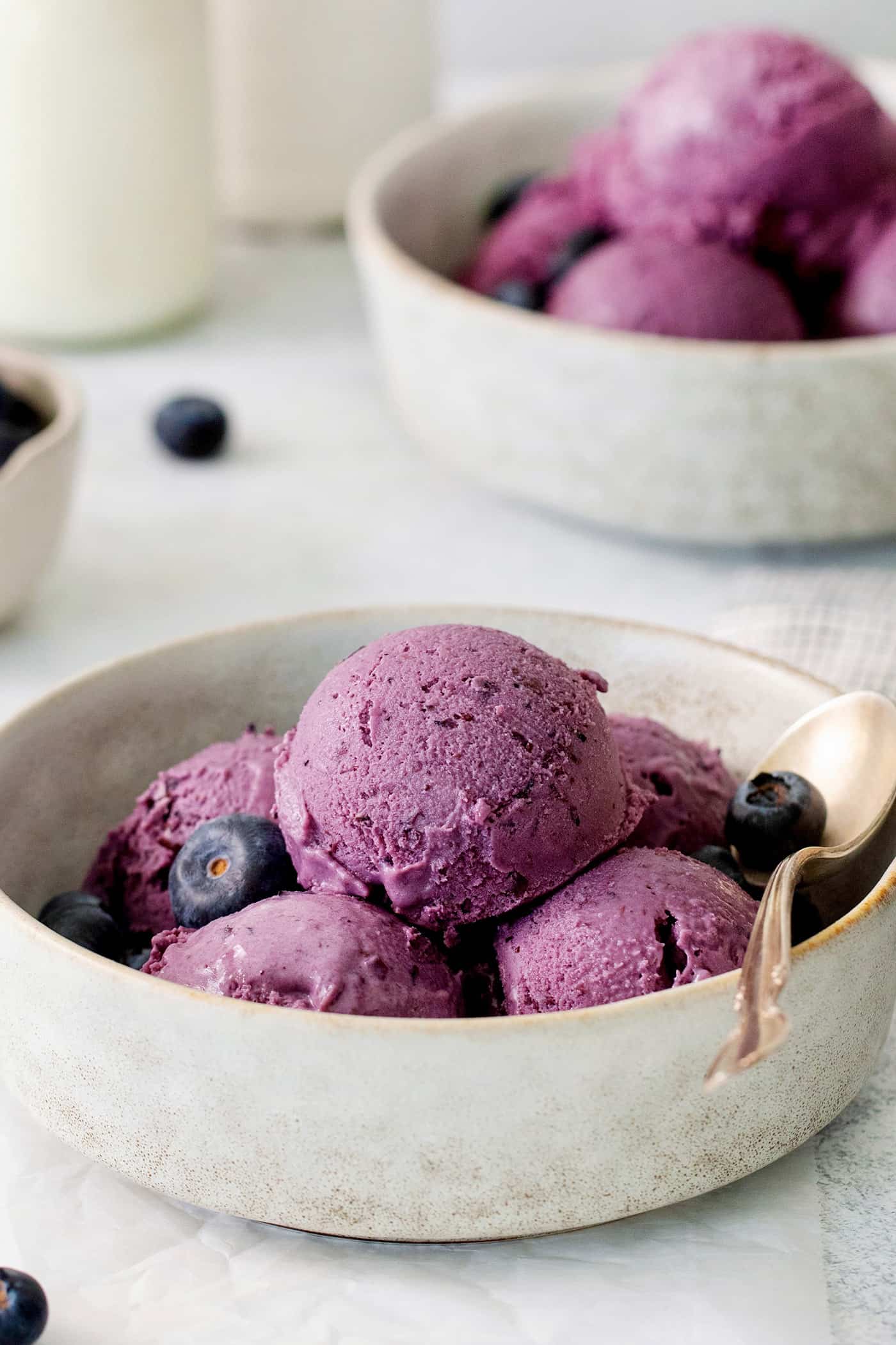 Scoops of blueberry ice cream in a white bowl.