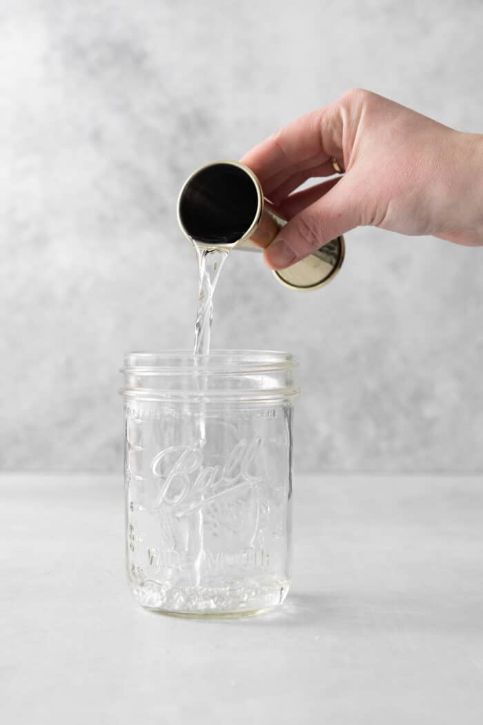White rum being poured into a mason jar