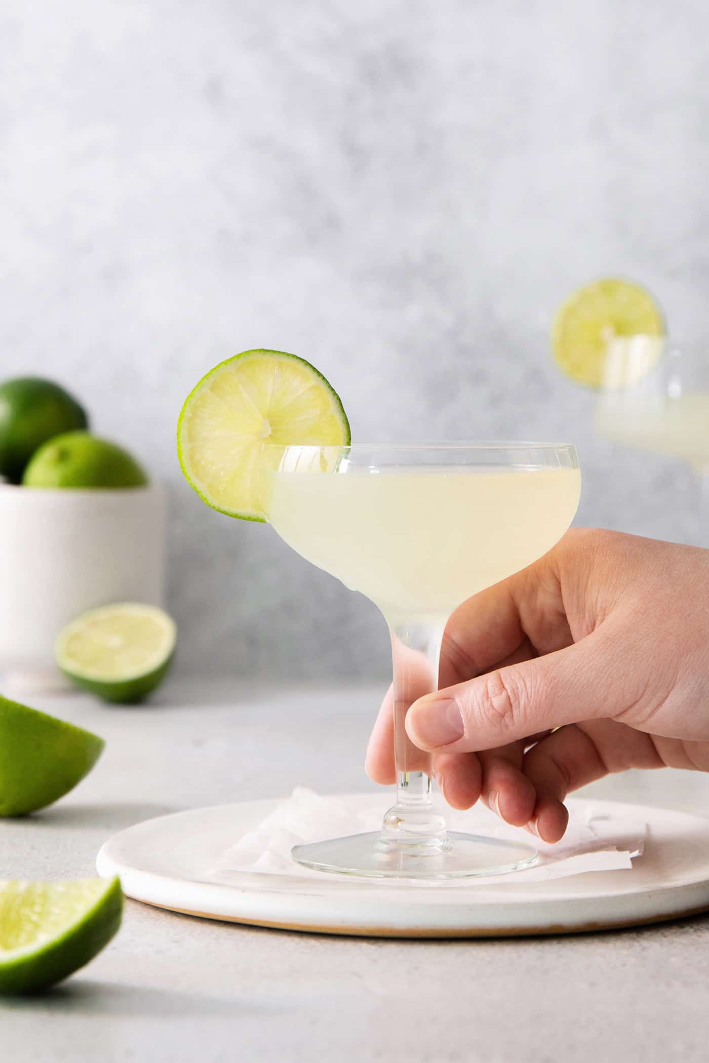 A hand grabbing a daiquiri in a coupe glass