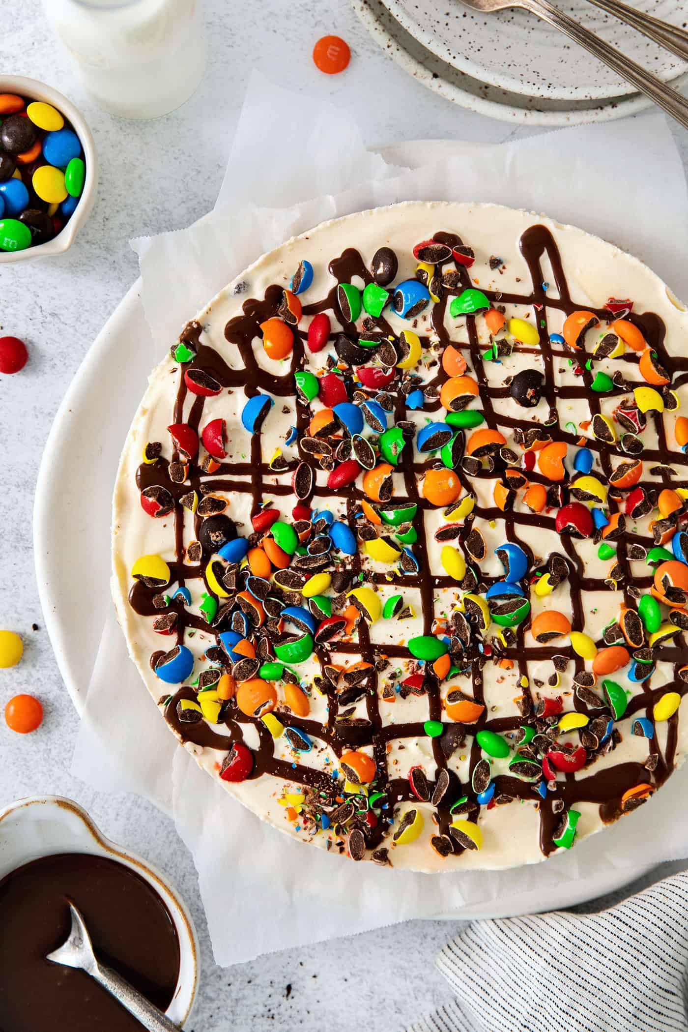 Overhead view of a homemade ice cream pizza with M&Ms and hot fudge topping.