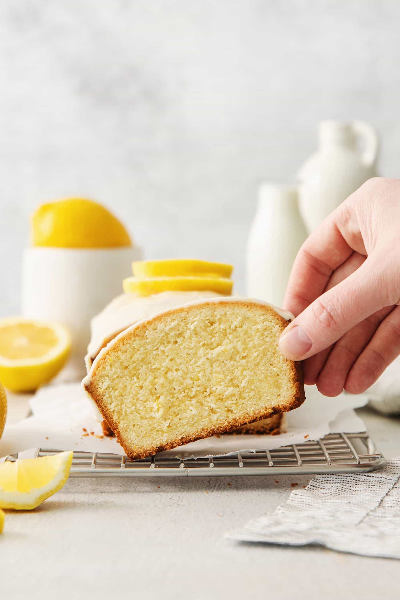 A hand picks up a slice of lemon pound cake.