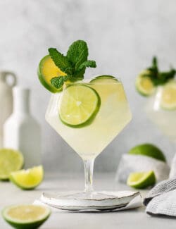 Classic mojitos are shown in glasses topped with mint and lime.