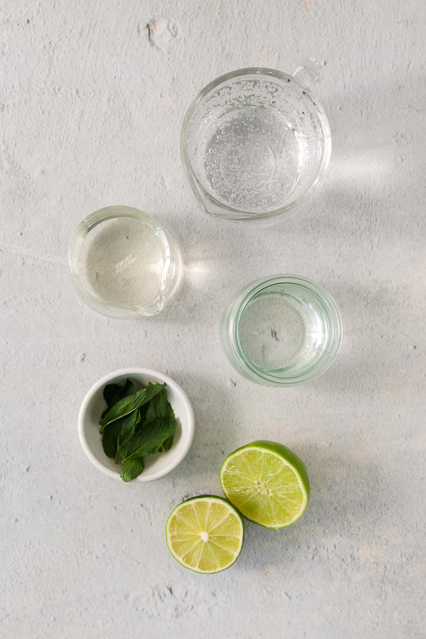 Ingredients for a classic mojito - rum, mint, simple syrup, lime juice, lime.