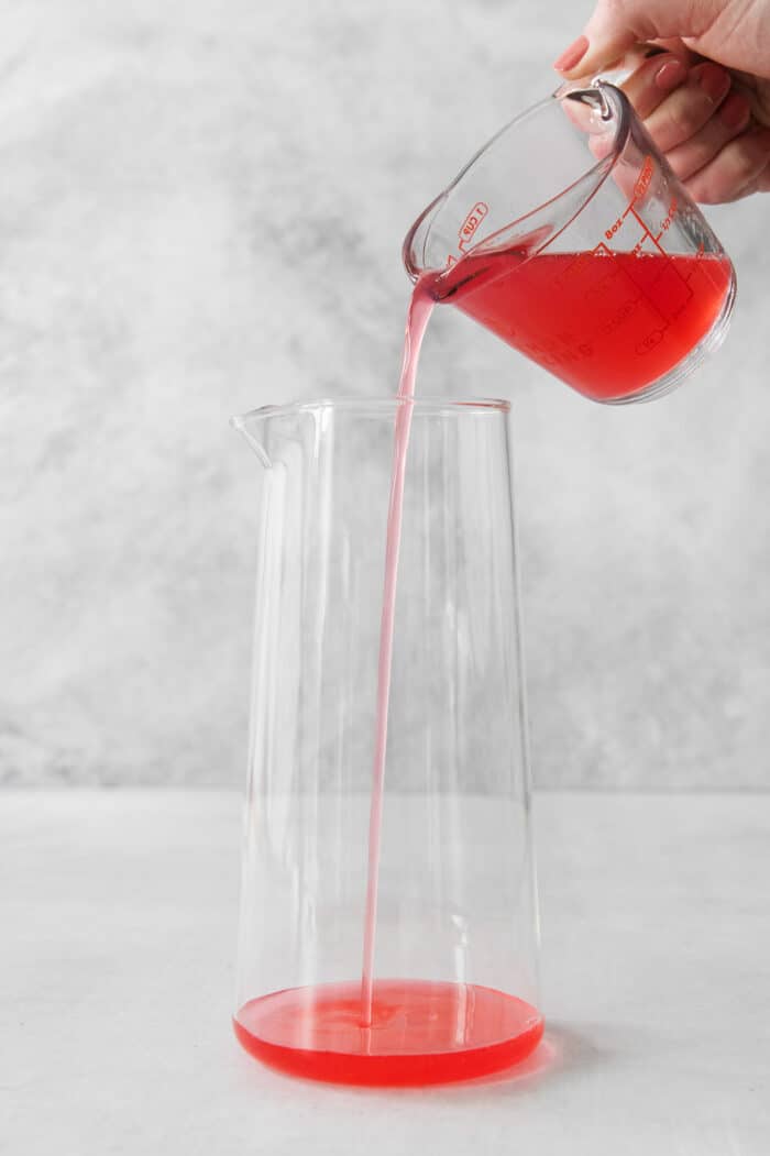 pouring rhubarb syrup into a pitcher