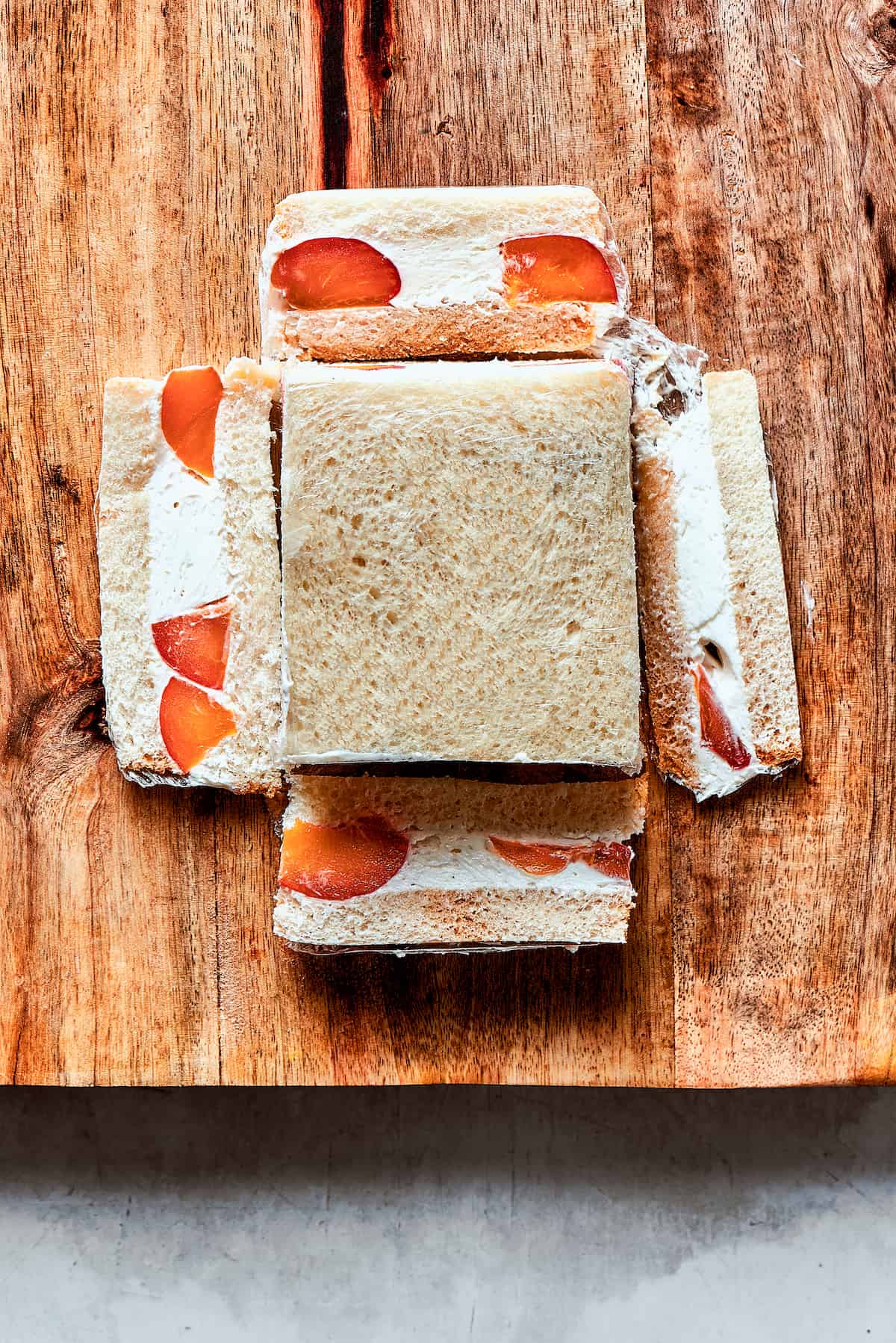 cutting a fruit sando on a wood cutting board