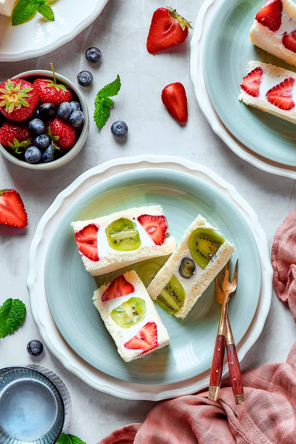 Slices of fruit sando on a plate with forks.