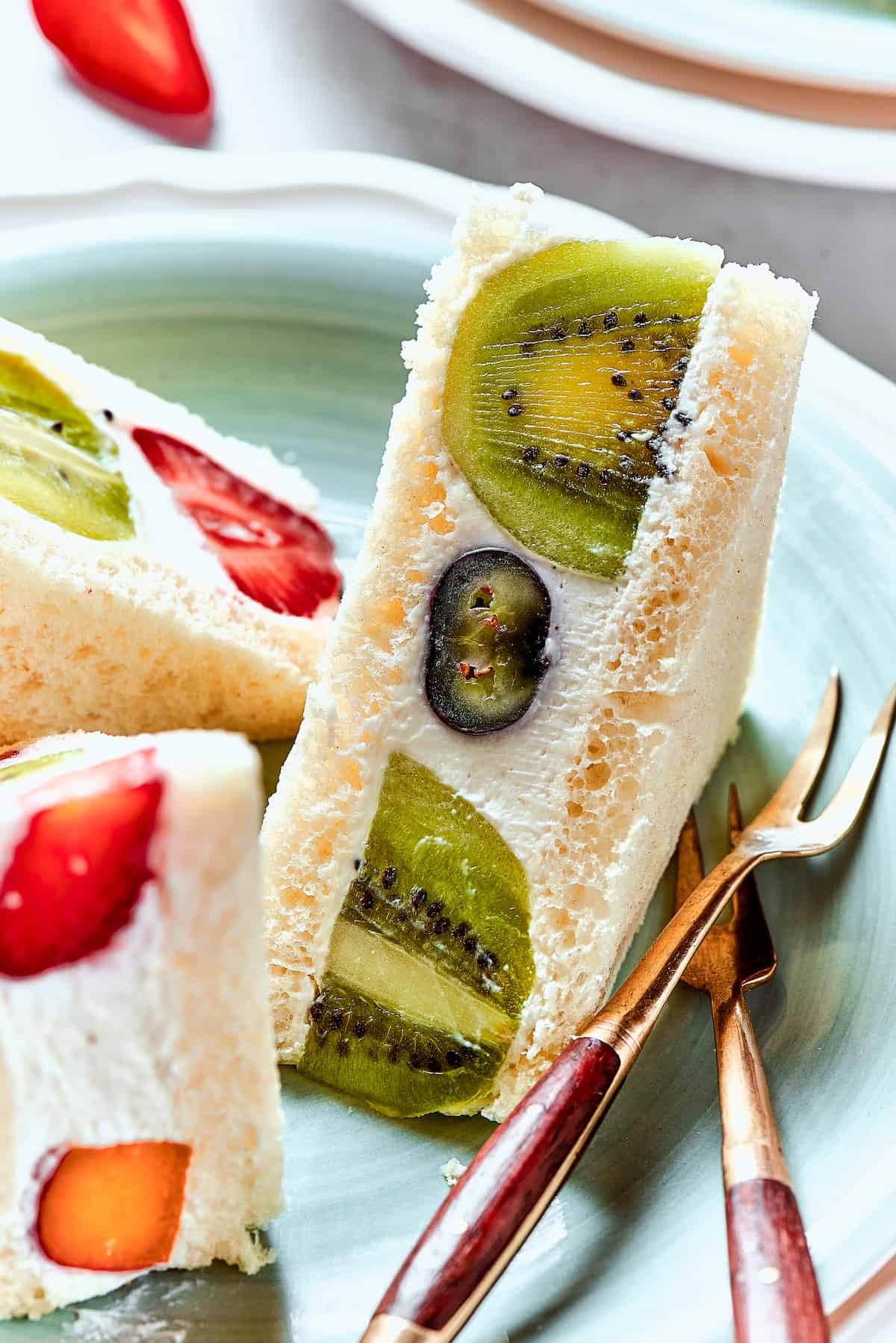 Slices of fruit sando on a plate with a fork.