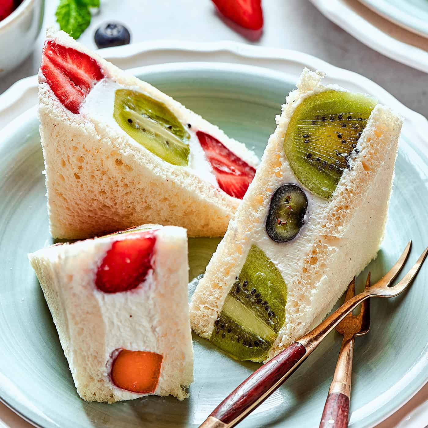 sandwich triangles made with soft bread, fluffy whipped cream, and fresh fruit